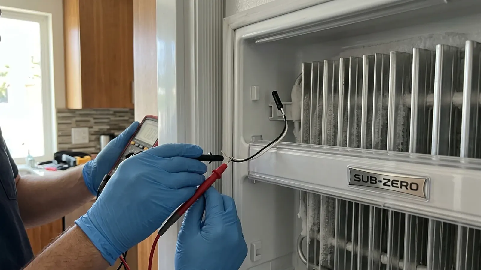 Technician testing the main control board on a Sub-Zero refrigerator in a DC Ranch home